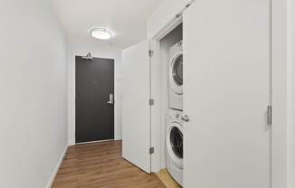 a washer and dryer in a white room with a black door