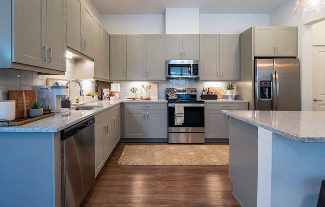 A modern kitchen with wooden floors and stainless steel appliances.