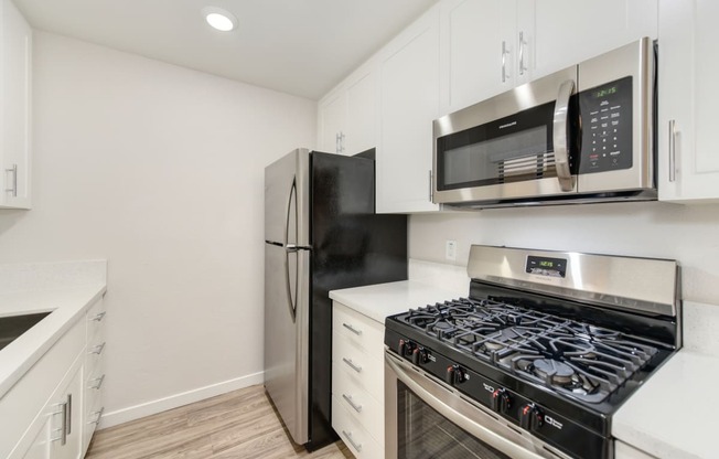 a kitchen with white cabinets and stainless steel appliances and a refrigerator