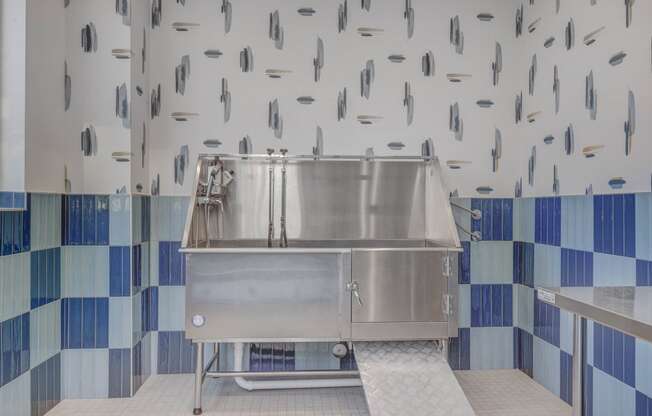 a large stainless steel sink in a kitchen with blue and white tiles