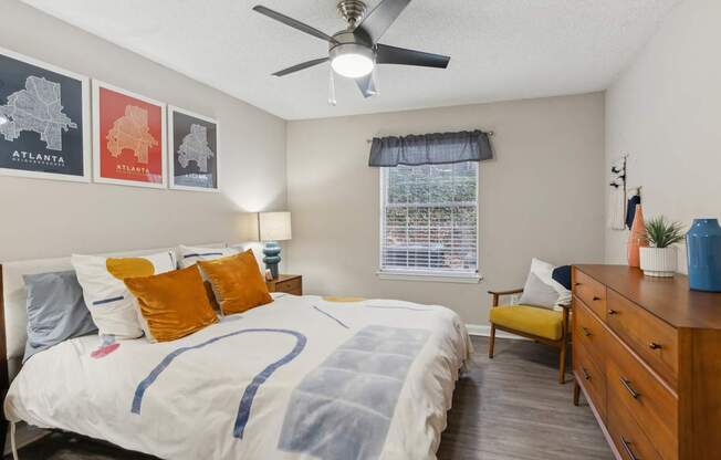 A bedroom with a bed, a dresser, and a ceiling fan.