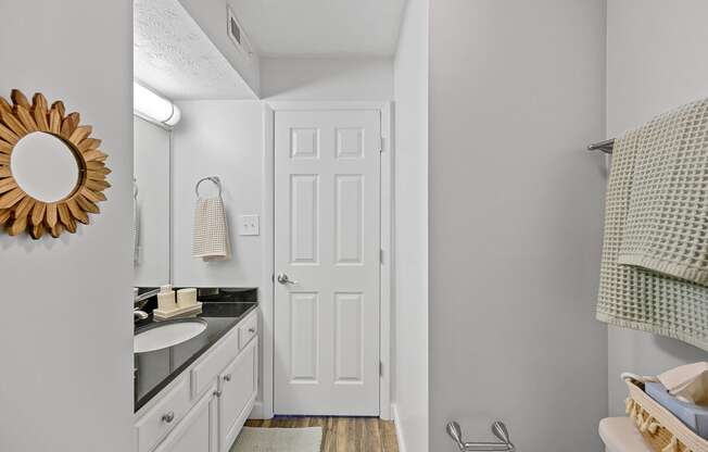 a bathroom with a white door and a sink and a mirror