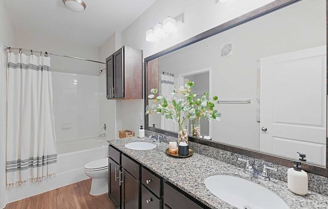 a bathroom with two sinks and a shower and a toilet