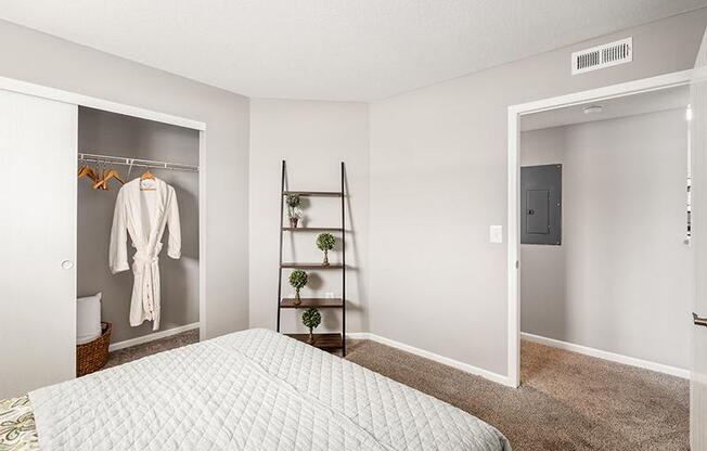 A bedroom with a bed, a closet, and a shelf.