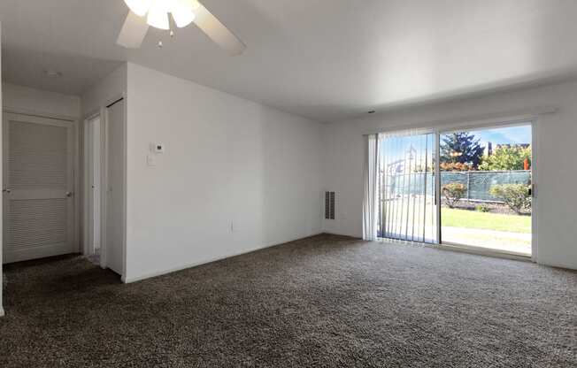 an empty living room with white walls and a sliding glass door