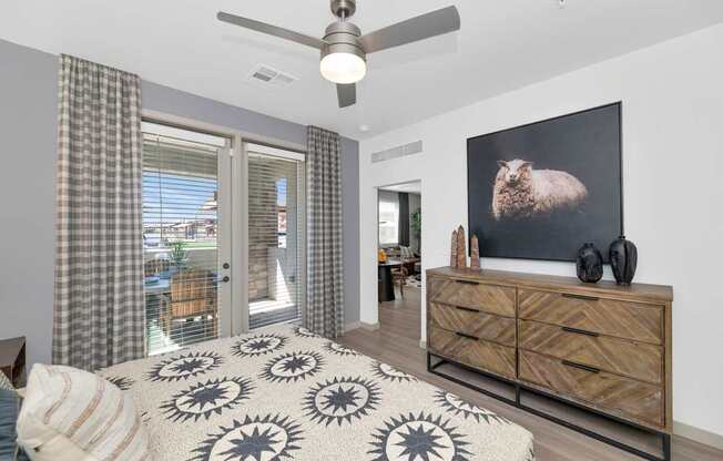 A bedroom with a bed, a dresser, and a ceiling fan.