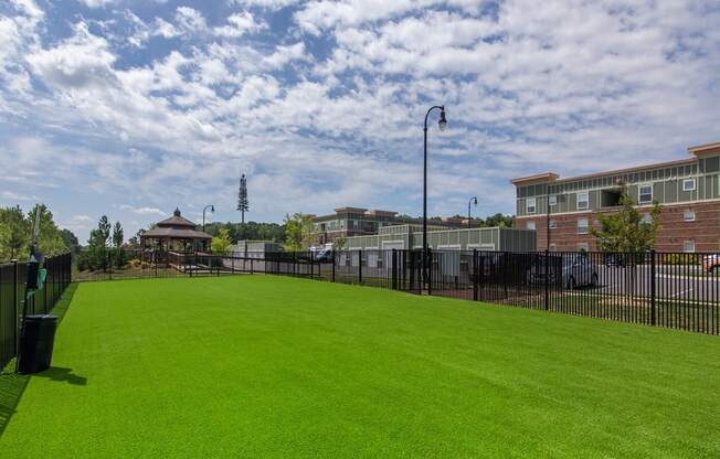 a grassy area with a gazebo and buildings in the background