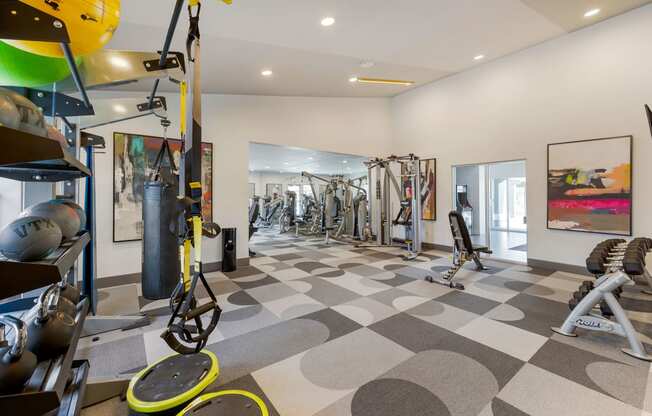 a gym with weights and cardio equipment on a checkered floor at Paisley and Pointe Apartments, Las Vegas, NV 89130