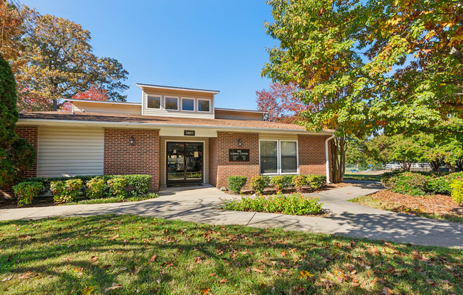 the front of a brick house with a yard and trees