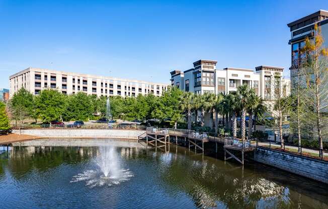 a fountain in a pond with buildings in the background