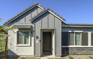 a gray house with a black door and a blue sky