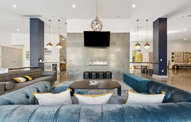 A modern living area with a blue velvet sofa and a television mounted on the wall.