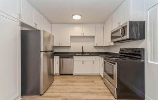 Model Kitchen with White Cabinets and Wood-Style Flooring at Palmilla Apartments located in San Diego, CA.