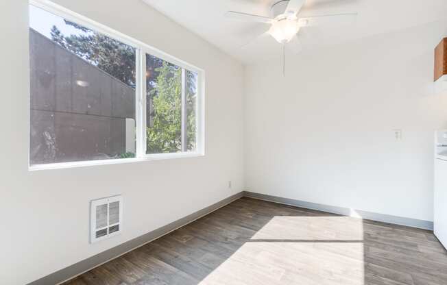 an empty room with a large window and a ceiling fan