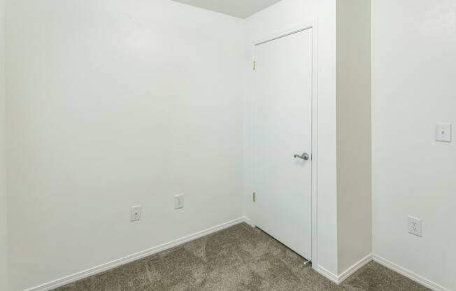 a bedroom with white walls and carpet and a white door