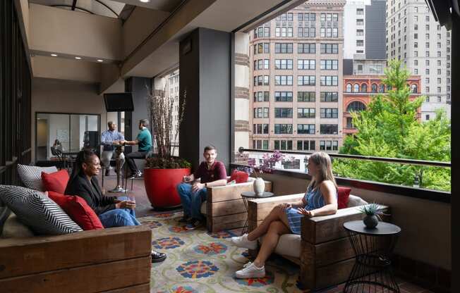 people sit on couches and chairs in a lobby with a large window