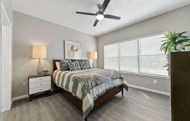 a bedroom with a large window and a ceiling fan