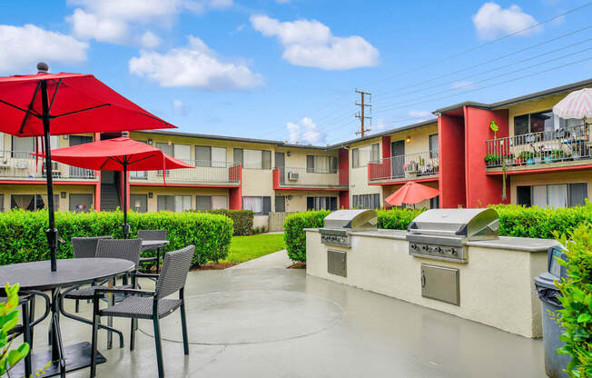 a patio with tables and umbrellas in front of apartments at Sunset Square, West Covina California