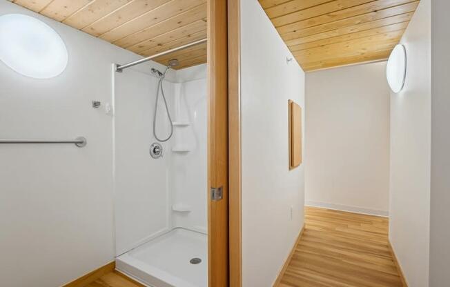 A bathroom with a wooden ceiling and a white shower.