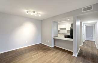 Living room and kitchen of an apartment with wood flooring and white walls  at Governors House, Huntsville