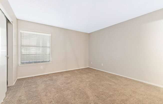 a bedroom with beige carpet and a window