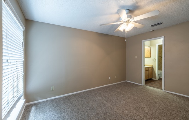 A room with a ceiling fan and carpeted floor.