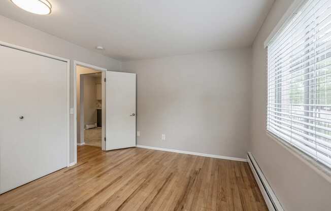 an empty living room with wood flooring and a large window