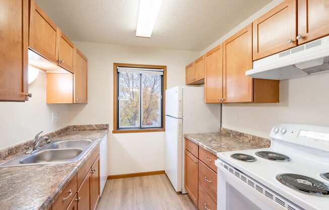 an empty kitchen with a stove refrigerator and sink. Fargo, ND Flagstone Apartments