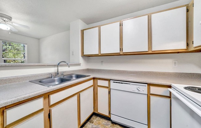 an empty kitchen with white appliances and wooden cabinets