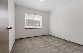 A room with a carpeted floor and a window with blinds.
