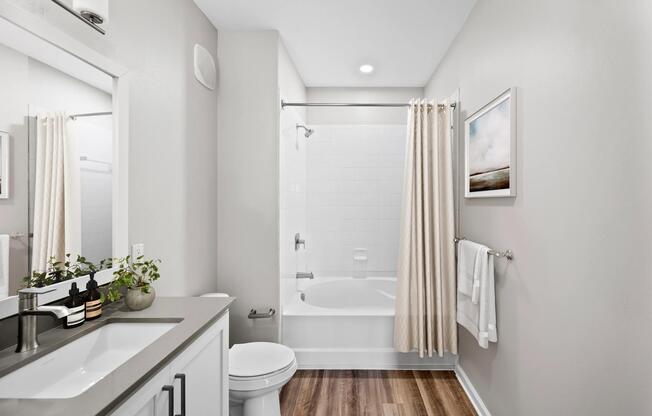 Bathroom with a quartz vanity, wood-style flooring, and a full tub-and-shower combination designed for comfort, convenience, and daily routines.