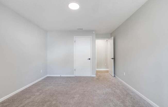A room with a carpeted floor and a white door.