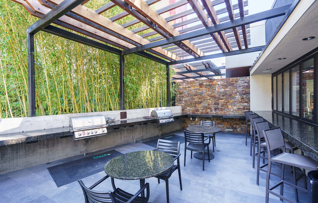 A patio with a table and chairs is surrounded by a bamboo wall.