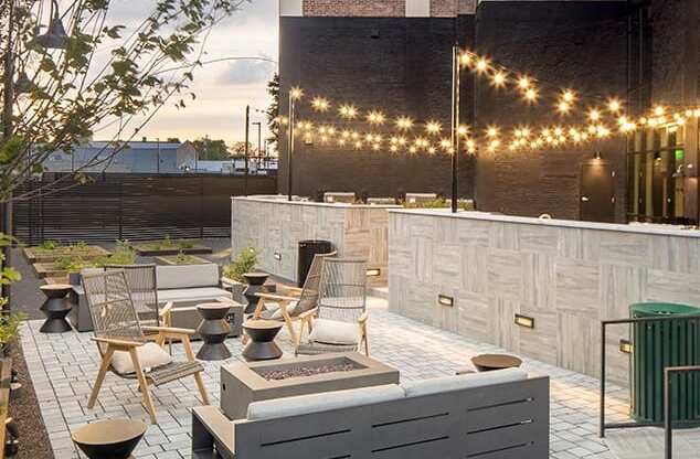 A patio with a fire pit and chairs.