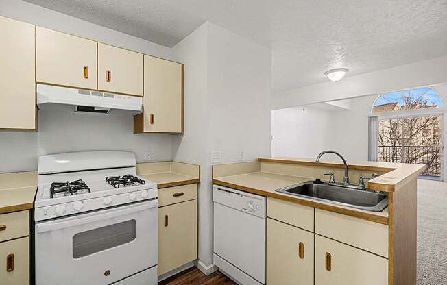 A kitchen with a white stove and beige cabinets.
