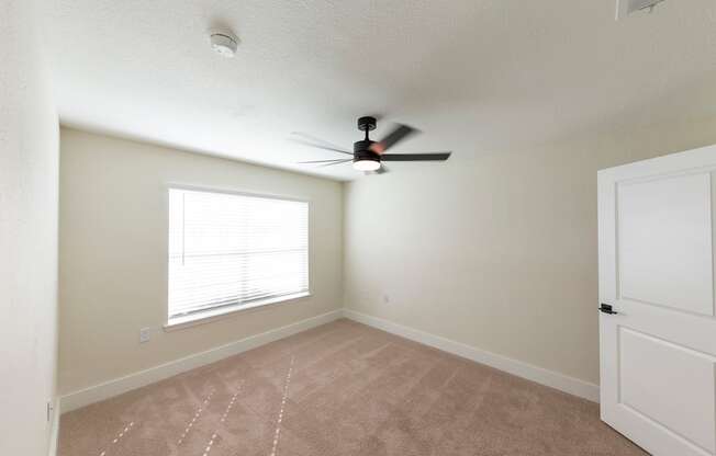 A room with a ceiling fan and a window with blinds.