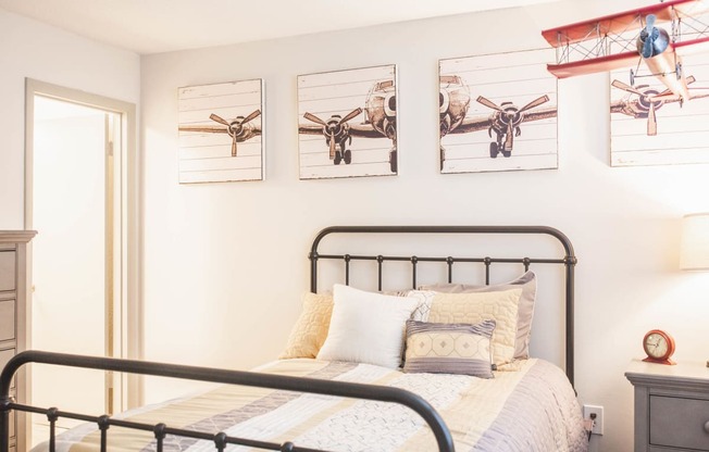 a bedroom with a bed and pictures of planes on the wall