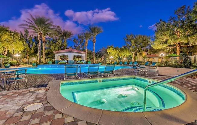 a pool with chairs and a hot tub at night at Mirasol Apartments, Las Vegas, NV 89119