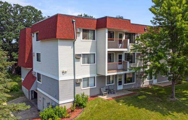 a white and red apartment building with a yard and trees
