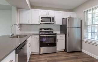 an empty kitchen with white cabinets and stainless steel appliances