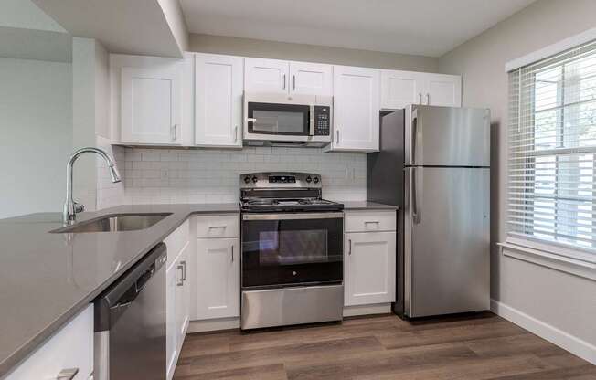 an empty kitchen with white cabinets and stainless steel appliances