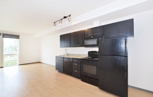 a kitchen with black cabinets and a wooden floor