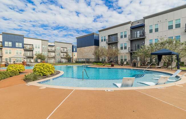 a swimming pool at an apartment complex with chairs around it