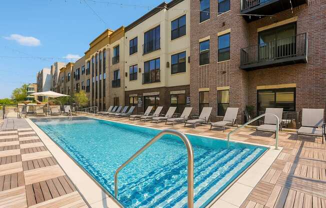 A pool surrounded by lounge chairs in front of a building.