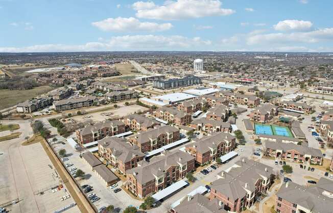 A bird's eye view of a residential area with apartment buildings and a pool.