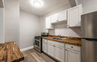 a kitchen with white cabinets and stainless steel appliances and a wooden counter top