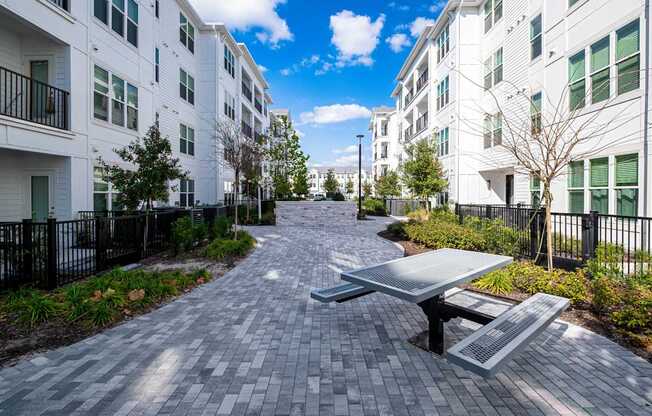 A long brick walkway leads to a white building with a black fence on the side.