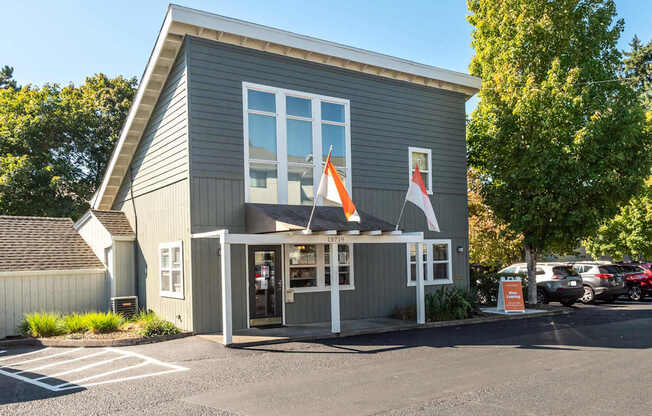 A grey building with a white awning and a red and white flag hanging from it.