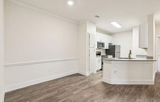 A large dining room area and a renovated kitchen with white cabinets, granite countertops through out and stainless steel appliances