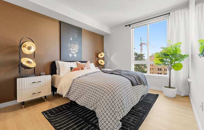 A bedroom with a large bed and a view of a construction site outside the window.